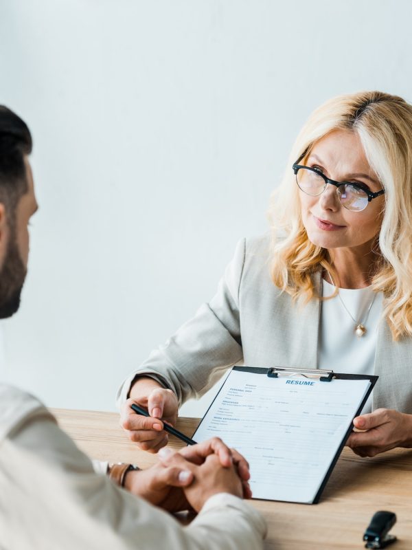 selective-focus-of-recruiter-in-glasses-holding-pen-near-clipboard-and-looking-at-bearded-man.jpg
